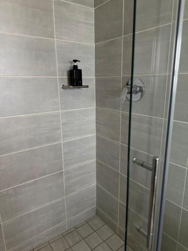 a shower with a glass door and a suitcase on a shelf at Zuri Marula Luxe in Midrand