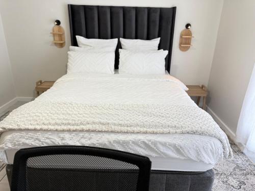 een bed met een zwart hoofdeinde en witte lakens en kussens bij Zuri Marula Luxe in Midrand