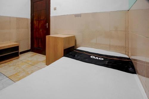 a small room with a bed and a wooden door at OYO 95035 Harmony Guest House Syariah Sawojajar in Ngadipuro
