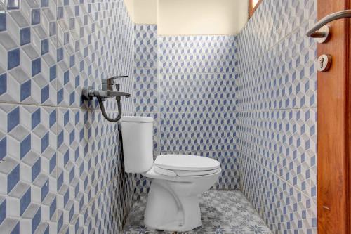 a bathroom with a toilet in a blue tiled wall at OYO 95019 Jeppi Homestay in Kedungsari
