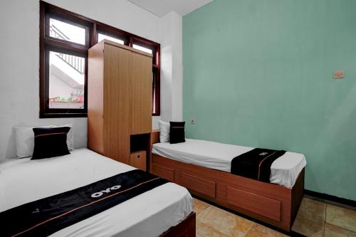 a room with two beds and a window at OYO 95035 Harmony Guest House Syariah Sawojajar in Ngadipuro