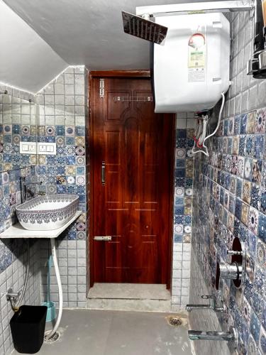 a bathroom with a wooden door and a sink at Baidehi Cottage in Rishīkesh
