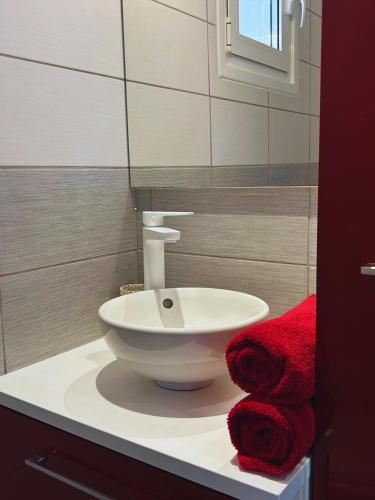 a bathroom with a white sink and red towels at Le cocon bleu, duplex cosy et lumineux in Précy-sur-Oise