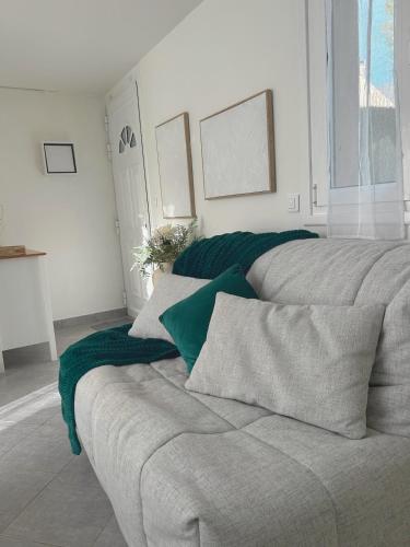 a couch with a green blanket on it in a room at Le cocon bleu, duplex cosy et lumineux in Précy-sur-Oise