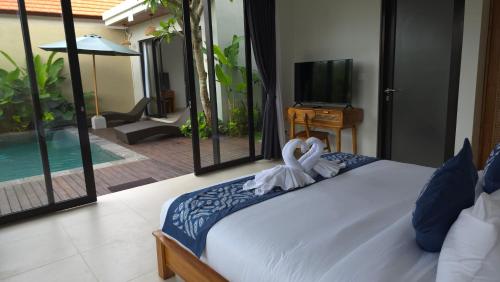 a bedroom with a bed and a tv and a pool at Adyatma Ubud in Ubud