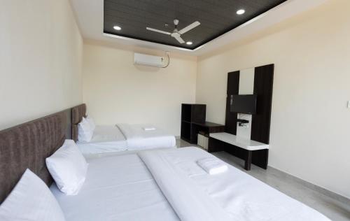 a bedroom with two beds and a tv in it at Hotel Basil Inn in Ujjain