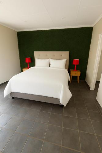 1 dormitorio con 1 cama blanca grande y pared verde en Hippo Zwartkop Suites, en Centurion