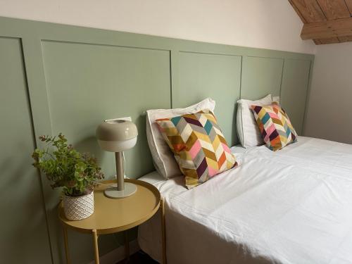 a bed with two pillows and a table with a lamp at A Casiña da Ponte in Lugo