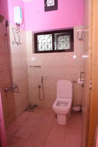 a bathroom with a white toilet and a window at The Arena Edava in Paravūr