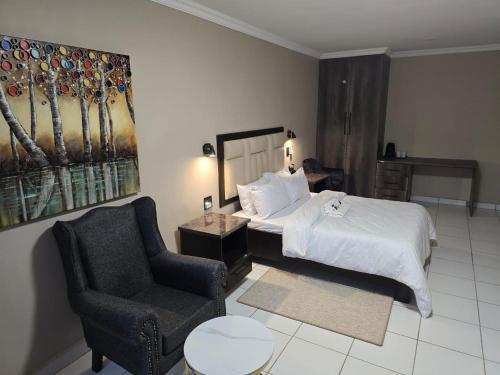 a hotel room with a bed and a chair at La Majestic Guest Lodge in Centurion