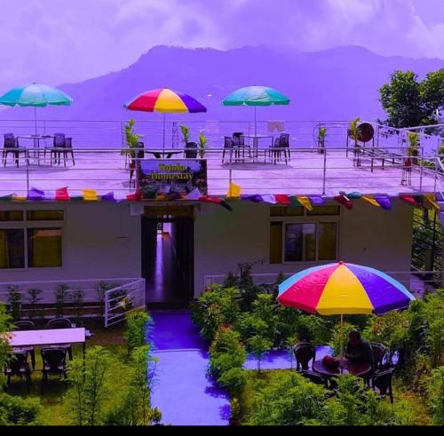 a patio with tables and umbrellas in front of a building at Aman magic resort in Takdāh