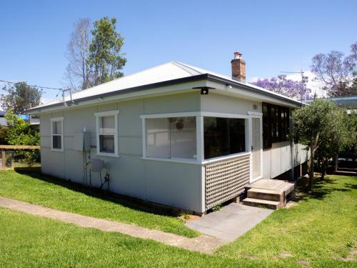 ein weißes Haus mit einer Veranda auf einem Hof in der Unterkunft Jerrinja - Absolute waterfront with jetty - 5 mins to Hyams Beach in Erowal Bay