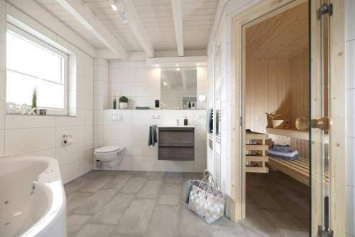 诺德霍恩Haus Norwald - tolles Ferienhaus direkt am See für bis zu 4 Personen mit Sauna und Kaminofen - Haustiere herzlich willkommen的带浴缸水槽和卫生间的浴室