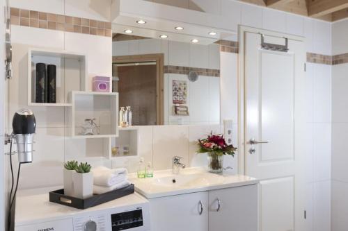 特希尔Schwalbennest Greetsiel für bis zu 6 Personen mit Kaminofen, Whirlpool und Sauna - Haustiere herzlich willkommen, nah am Hafen的一间白色浴室，配有洗手池和镜子。