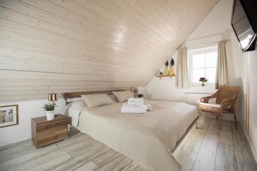 特希尔Schwalbennest Greetsiel für bis zu 6 Personen mit Kaminofen, Whirlpool und Sauna - Haustiere herzlich willkommen, nah am Hafen的卧室里有一张白色的大床和一把椅子