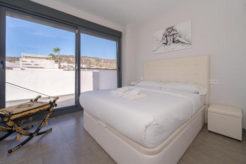 a white bedroom with a bed and a large window at Villa La Finca Golf in Algorfa