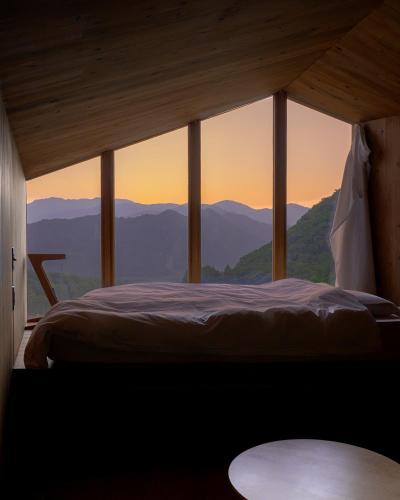 a bedroom with a bed with a view of mountains at Earthboat Minakami Fujiwara in Sudagai