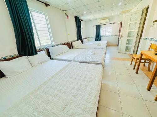 una habitación con una fila de camas y una mesa en Hoài Thu Hotel Vũng Tàu, en Vung Tau