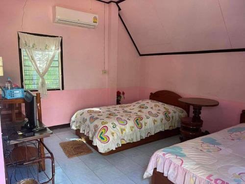 a bedroom with two beds and a tv in it at เฮินไตเกสเฮาส์ in Ban Nong Pa Ko