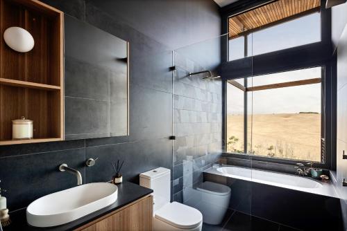 a bathroom with a sink toilet and a window at Studio on Forktree – Modern Coastal Retreat in Carrickalinga