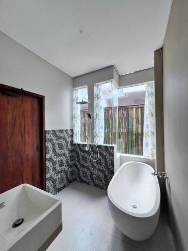 ein Badezimmer mit einer großen weißen Badewanne und einem Waschbecken in der Unterkunft The Inside House Medewi in Airsatang