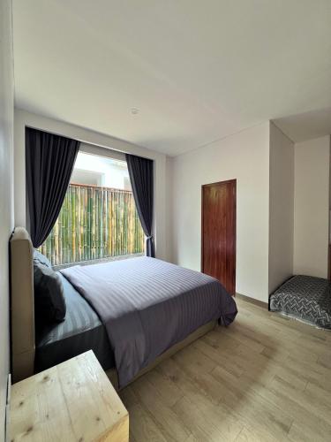 ein Schlafzimmer mit einem Bett und einem großen Fenster in der Unterkunft The Inside House Medewi in Airsatang