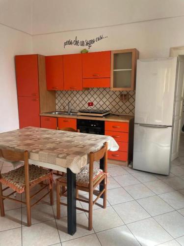a kitchen with red cabinets and a table and a refrigerator at dimora princ di napoli 14 in Polignano a Mare