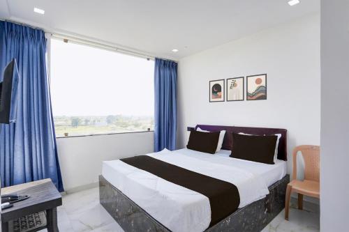 um quarto com uma cama com cortinas azuis e uma janela em Collection O Hingna City Court Nagpur Formerly Hotel Dream Inn em Khāpri