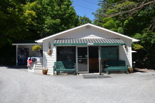 a small building with two green benches in front of it at Lake View Motel in Cooperstown