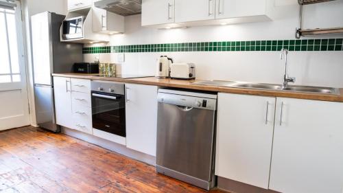 Dalebrook Place - Unit 6 في كالكباي: مطبخ مع دواليب بيضاء وغسالة صحون حديد قابلة للصدأ