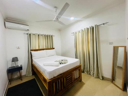 a bedroom with a bed with white sheets and curtains at Vuga Town House in Zanzibar City