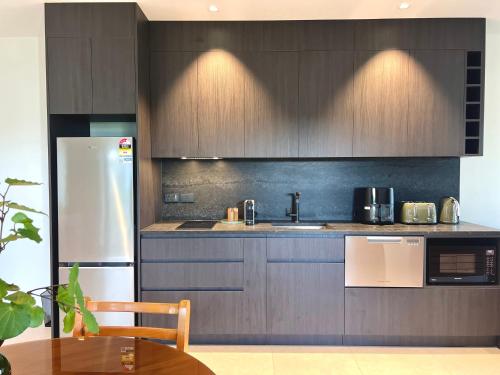 a kitchen with wooden cabinets and a white refrigerator at Mangawhai Estuary Escape in Mangawhai