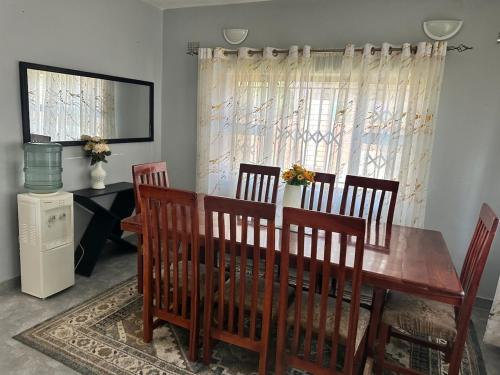 ein Esszimmer mit einem Holztisch und Stühlen in der Unterkunft Hatfield Staylax Manor 4 in Harare