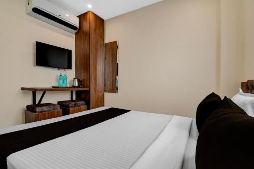 a bedroom with a white bed and a television at Hotel O Netaji Metro Station Kolkata Formerly Mahamaya Step Inn in Thakurpukur