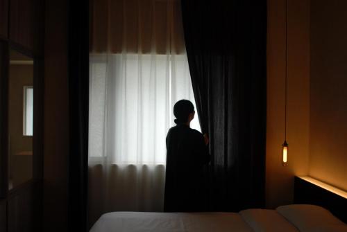 a woman is looking out of a window at 雲居月-kumoizuki- in Ginowan