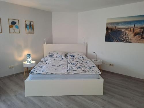 ein weißes Schlafzimmer mit einem Bett und zwei Tischen in der Unterkunft Ferienwohnung Kleine Auszeit im Hunsrück in Gaß