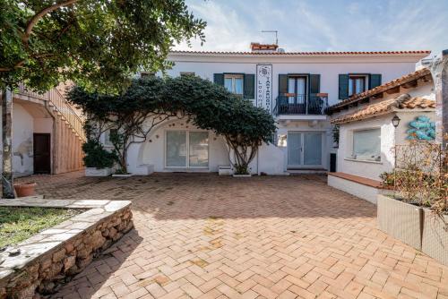a large white house with a brick driveway at Estay - Locanda Tartarughino in Porto Rotondo