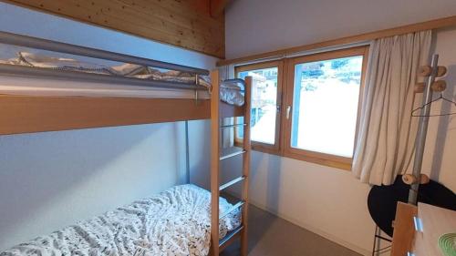 Un dormitorio con dos literas y una ventana. en Doberts 6, un duplex au pied des montagnes!, en Zinal