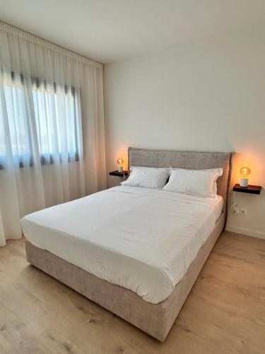 a bedroom with a large white bed with two lamps at Sunset Gardens - Holiday Apartments in Limassol
