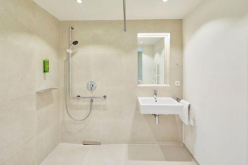 a white bathroom with a shower and a sink at Tagungshotel Kloster Untermarchtal in Untermarchtal