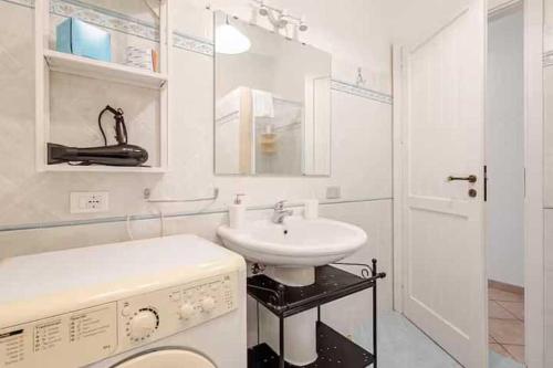 biała łazienka z umywalką i pralką w obiekcie Villa Uzzo by Sicily Travelling Villas w mieście Scopello