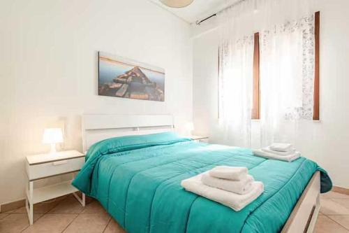 biała sypialnia z niebieskim łóżkiem i ręcznikami w obiekcie Villa Uzzo by Sicily Travelling Villas w mieście Scopello