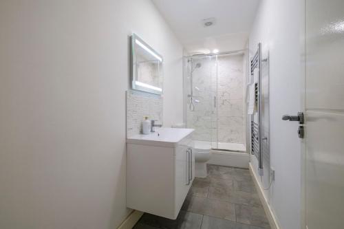 Un baño blanco con lavabo y ducha en 2 Bedroom Spacious Apartment, Free Parking, WiFi, en Gloucester