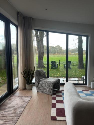 a living room with a couch and a large window at Tiny forest house met vrij uitzicht in Putten