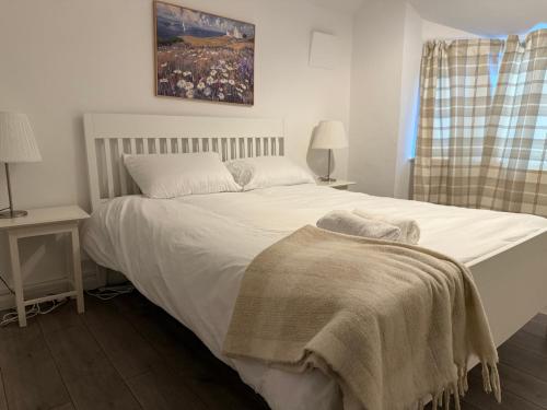 ein Schlafzimmer mit einem weißen Bett mit einer Decke darauf in der Unterkunft Cosy 3 Bedroom Home, Parking & Bus in Oxford