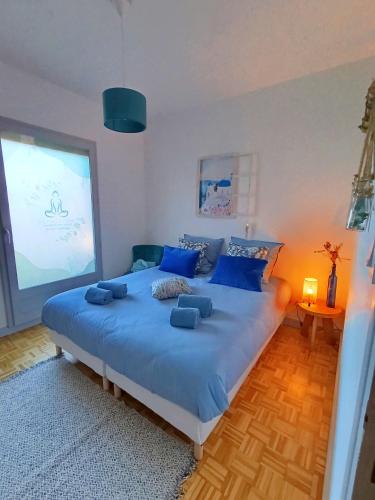 ein Schlafzimmer mit einem großen blauen Bett mit blauen Kissen in der Unterkunft Maison d'hôtes Ma Parenthèse in Saint-Christo-en-Jarez