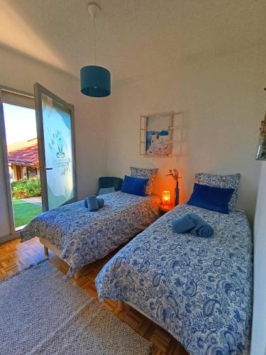 ein Schlafzimmer mit zwei Betten mit blauer Bettwäsche und einem Fenster in der Unterkunft Maison d'hôtes Ma Parenthèse in Saint-Christo-en-Jarez