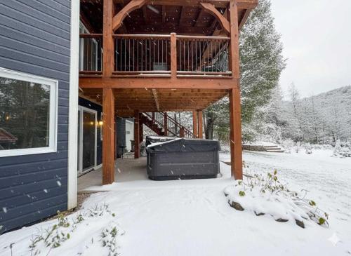 una casa in legno con una terrazza nella neve di Spa Nature Waterfront - Le Cardinal a Ripon