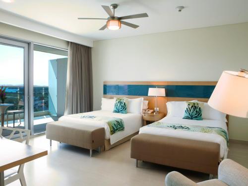 a hotel room with two beds and a balcony at Las Americas Torre Del Mar in Cartagena de Indias