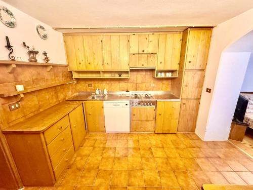 Cozy Apartment - Alverà في كورتينا دامبيتزو: مطبخ بدولاب خشبي وغسالة صحون بيضاء